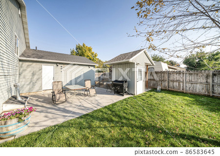 Backyard of a house with white back door and two lounge chairs and table 86583645