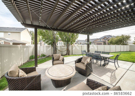 Woven armchairs with cushion and dining table under the pergola roof 86583662