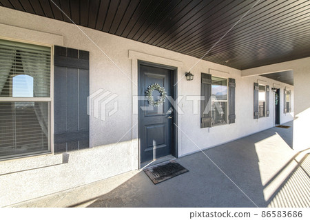 Black front doors of apartment units with wreaths and wall lamps 86583686
