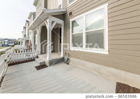 Front entrance of a light brown townhouse with white picket fence 86583986