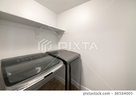 Two laundry appliances with reflective glass inside a laundry room Two laundry appliances with reflective glass inside a laundry room 86584005