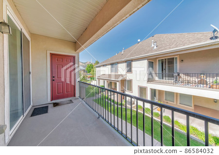 Veranda of a house with red wooden door and sliding glass door Veranda of a house with red wooden door and sliding glass door 86584032
