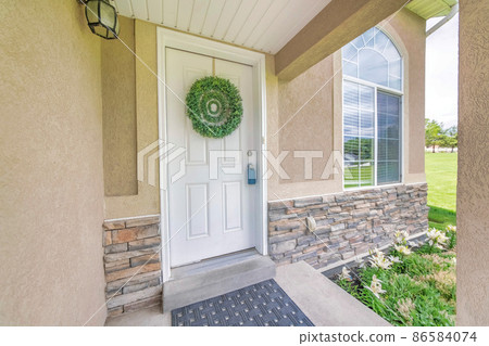 White front door with leafy wreath and lockbox on the handle 86584074
