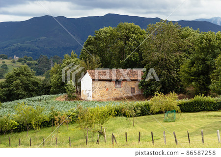 Scenic view of valley in Asturias with traditional farm building Scenic view of valley in Asturias with traditional farm building 86587258