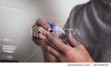 A close-up of the hands of an unrecognizable man gluing the base for fixing a ceiling lamp with glue. Repair 86589930