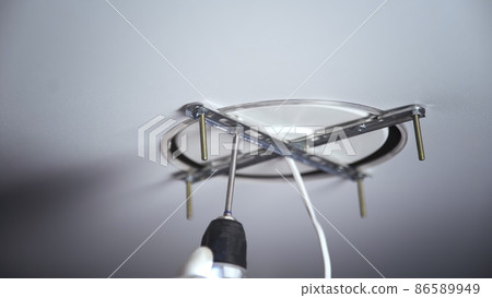 A close-up of the hands of an unrecognizable man drilling the base for mounting a ceiling light. Repair A close-up of the hands of an unrecognizable man drilling the base for mounting a ceiling light. Repair 86589949