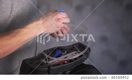 A close-up of the hands of an unrecognizable man gluing the base for fixing a ceiling lamp with glue. Repair A close-up of the hands of an unrecognizable man gluing the base for fixing a ceiling lamp with glue. Repair 86589952