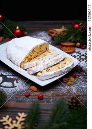 Sliced Traditional Christmas stollen cake with marzipan and dried fruit on wooden background Sliced Traditional Christmas stollen cake with marzipan and dried fruit on wooden background 86590243
