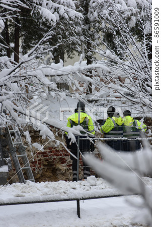 Workers in uniform reconstructing the old wall. Winter on the street 86591009