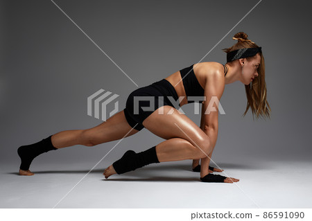 Animal instinct fitness female instructor showing his incredible flexibility with an animal flow move in studio against a gray background Animal instinct fitness female instructor showing his incredible flexibility with an animal flow move in studio against a gray background 86591090