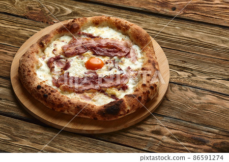 Carbonara pizza with bacon and egg on wooden background Carbonara pizza with bacon and egg on wooden background 86591274