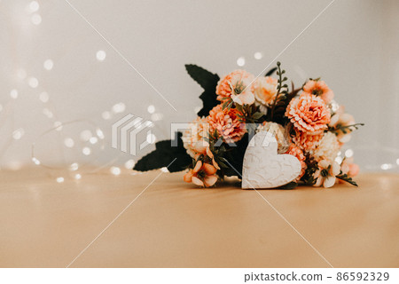 wooden table with a bouquet of flowers and a white heart 86592329