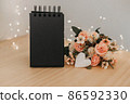 notebook with black sheets with copy space, a bouquet of flowers and a white heart 86592330