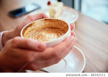 Woman have breakfast at cafe, hold coffee cap in hands 86592511