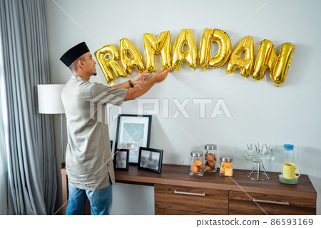 muslim male decorating the wall with ramadan balloon text 86593169