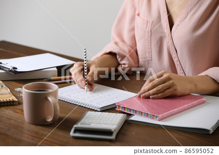 Woman marking date in calendar at wooden table, closeup 86595052