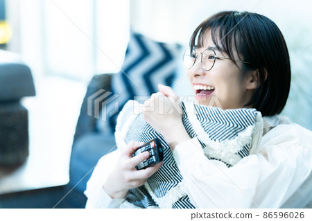 A young woman with glasses watching TV in the living room A young woman with glasses watching TV in the living room 86596026