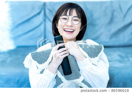 一位戴眼鏡的年輕女子在客廳看電視 一位戴眼鏡的年輕女子在客廳看電視 86596028