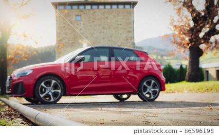 Blur red SUV parked at outdoor car parking lot of the city. Side view of EV car at parking lot. Electric vehicle concept. Road trip travel in Europe. Automotive industry. Environmental friendly car. 86596198