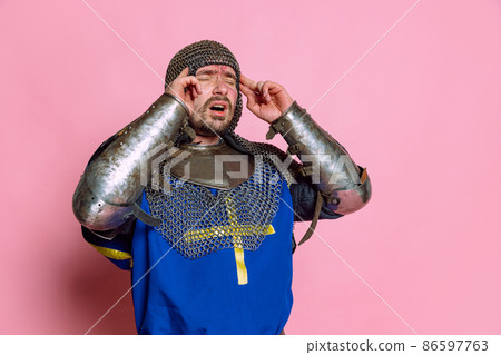 Portrait of man, medieval warrior or knight in armor suffering from pain, touching temples in headache isolated over pink studio background Portrait of man, medieval warrior or knight in armor suffering from pain, touching temples in headache isolated over pink studio background 86597763