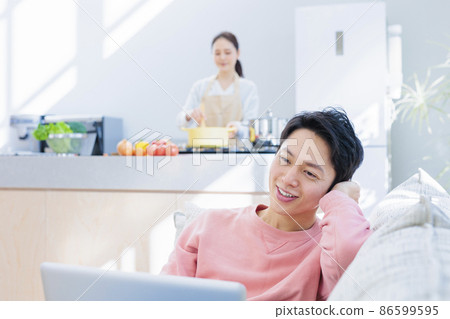 和丈夫一起做飯的妻子在家裡悠閒地對著電腦 86599595