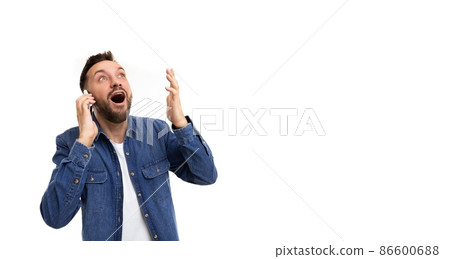 A man speaks on the phone gesturing with his hands with an open mouth, a smile and wide eyes in A man speaks on the phone gesturing with his hands with an open mouth, a smile and wide eyes in 86600688
