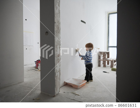 Adorable child painting white wall between two rooms under renovation. Cute baby boy using paint brush while renovating apartment. Concept of home renovation, refurbishment and childhood. 86601631