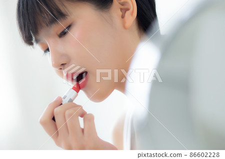 Beautiful young asian woman applying lipstick red on mouth, beauty girl looking facial at mirror. 86602228