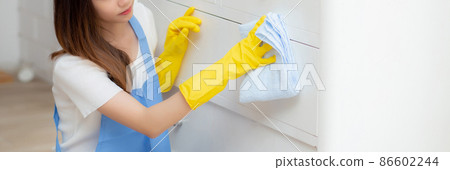 Young asian woman in face mask and gloves cleaning home in room. 86602244