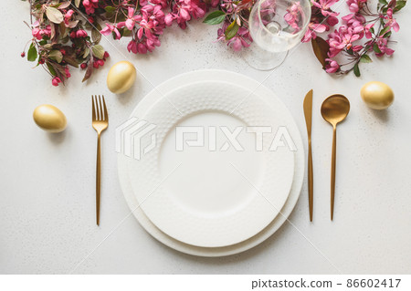 Easter dinner with eggs, bunny, festive tableware and tulips on white. 86602417