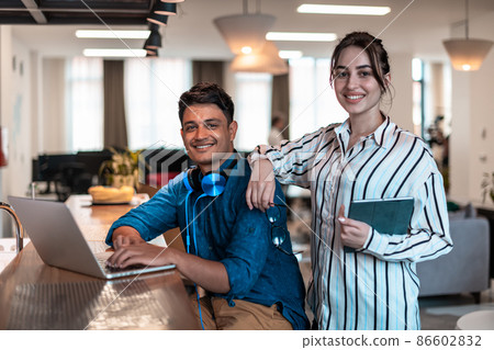 Multiethnic business people man with a female colleague working together on tablet and laptop computer in relaxation area of modern startup office 86602832