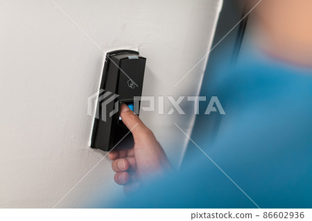 Man pressing fingerprint scanner on alarm system indoorsFinger print scan for unlock door security system 86602936