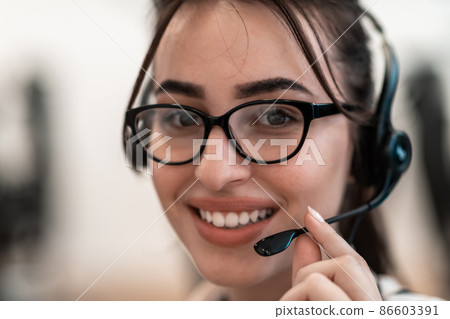 Business and technology concept - helpline female operator with headphones in call centre .Business woman with headsets working in a call center 86603391