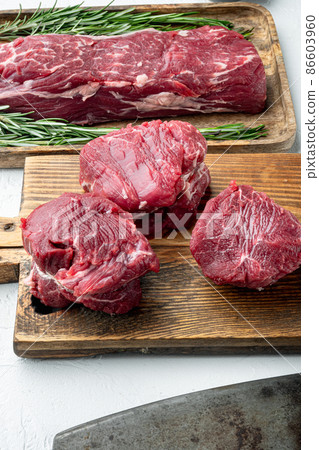 Raw beef fillet steaks with spices, on wooden cutting board, on white stone surface Raw beef fillet steaks with spices, on wooden cutting board, on white stone surface 86603960
