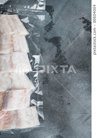 Raw haddock fish skinless, plastic vacuum packaged, on gray background, top view with copy space for text 86604004