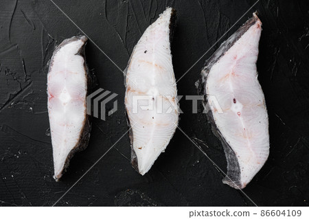 Frozen fillets of white fish, pollock, on black dark stone table background, top view flat lay 86604109