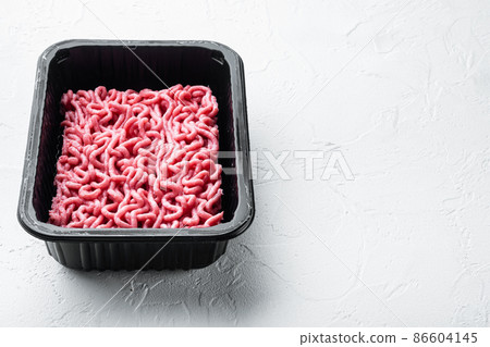 Minced meat in packaging, on white stone background, with copy space for text 86604145