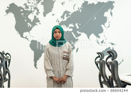 Portrait of muslim female software developer with green hijab standing at modern open plan startup office 86604244