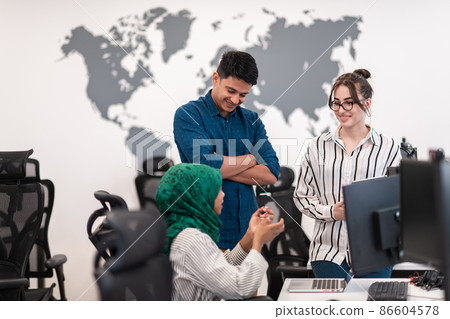 Multiethnic startup business team Arabian woman wearing a hijab on meeting in modern open plan office interior brainstorming, working on laptop and desktop computer. Selective focus Multiethnic startup business team Arabian woman wearing a hijab on meeting in modern open plan office interior brainstorming, working on laptop and desktop computer. Selective focus 86604578