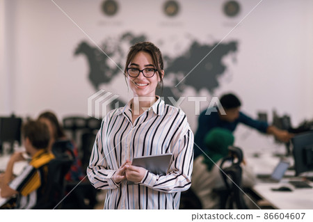 Portrait of businesswoman in casual clothes holding tablet computer at modern startup open plan office interior. Selective focus Portrait of businesswoman in casual clothes holding tablet computer at modern startup open plan office interior. Selective focus 86604607