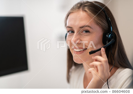 Helpline female operator with headphones in call centre.Business woman with headsets working in a call center. Selective focus Helpline female operator with headphones in call centre.Business woman with headsets working in a call center. Selective focus 86604608