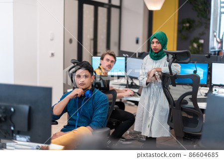 Multiethnic startup business team Arabian woman wearing a hijab on meeting in modern open plan office interior brainstorming, working on laptop and desktop computer. Selective focus Multiethnic startup business team Arabian woman wearing a hijab on meeting in modern open plan office interior brainstorming, working on laptop and desktop computer. Selective focus 86604685