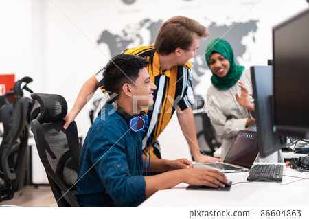 Multiethnic startup business team Arabian woman wearing a hijab on meeting in modern open plan office interior brainstorming, working on laptop and desktop computer. Selective focus Multiethnic startup business team Arabian woman wearing a hijab on meeting in modern open plan office interior brainstorming, working on laptop and desktop computer. Selective focus 86604863