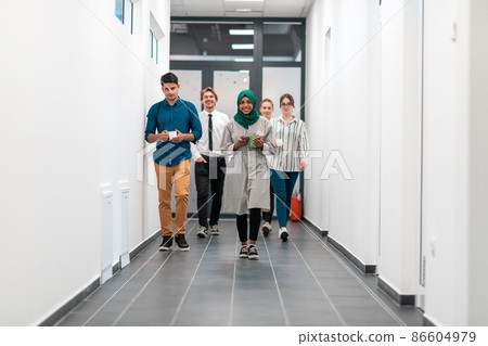 Multi-ethnic startup business team walking through the hallway of the building while coming back from a coffee break Multi-ethnic startup business team walking through the hallway of the building while coming back from a coffee break 86604979