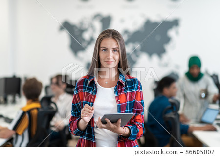 Portrait of businesswoman in casual clothes holding tablet computer at modern startup open plan office interior. Selective focus Portrait of businesswoman in casual clothes holding tablet computer at modern startup open plan office interior. Selective focus 86605002