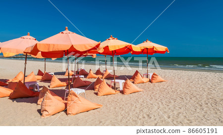 Orange umbrellas and bean bag chairs on sand beach Orange umbrellas and bean bag chairs on sand beach 86605191