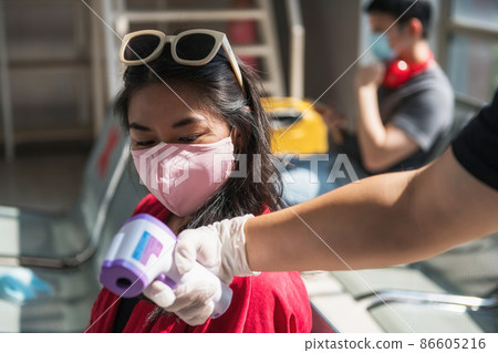 airport officer show temperature to passenger 86605216