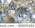 Chrystal chandelier blur sparkling rainbow bokeh background. Beautiful yellow and blue light reflecting through glass crystals hanging on chandelier. 86605484
