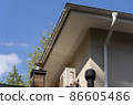 Exhaust air pipes, air conditioner and white rain gutter on private house roof. Metallic Guttering System and ventilation pipes exterior 86605486