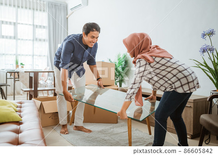 Attractive family of woman with hijab and man relocation furniture in new home 86605842